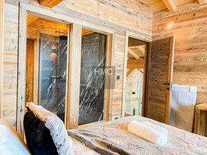 A wooden cabin interior with a bed, a shower area, and a door leading to another room. - The View face à l’infini, au cœur de la vallée (Bolquère)