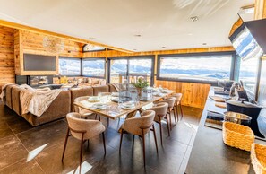 A modern interior with a dining area, sofa, and kitchen counter with a view. - The View face à l’infini, au cœur de la vallée (Bolquère)