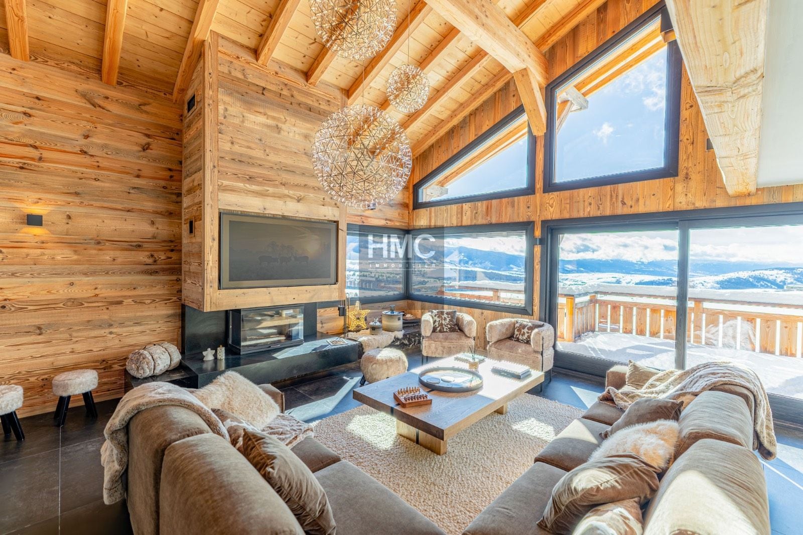 Una sala de estar acogedora con chimenea, asientos cómodos y un amplio ventanal con vistas a la montaña.