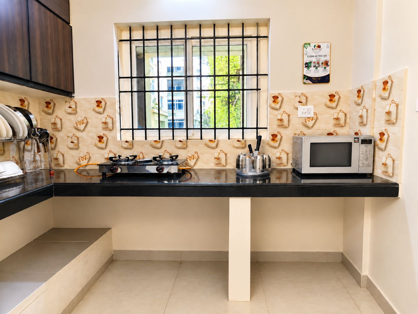 A kitchen with a gas stove, microwave, and a window with bars.