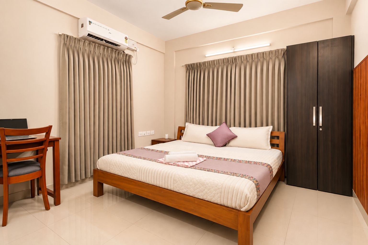 A bedroom with a bed, a desk, an air conditioning unit, a wardrobe, and a ceiling fan.