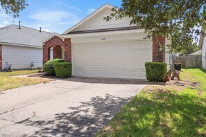 A residential garage with a brick archway, a white garage door, and a mailbox. - Cozy Modern 3br/2ba Retreat Near 3 Highways (Houston)