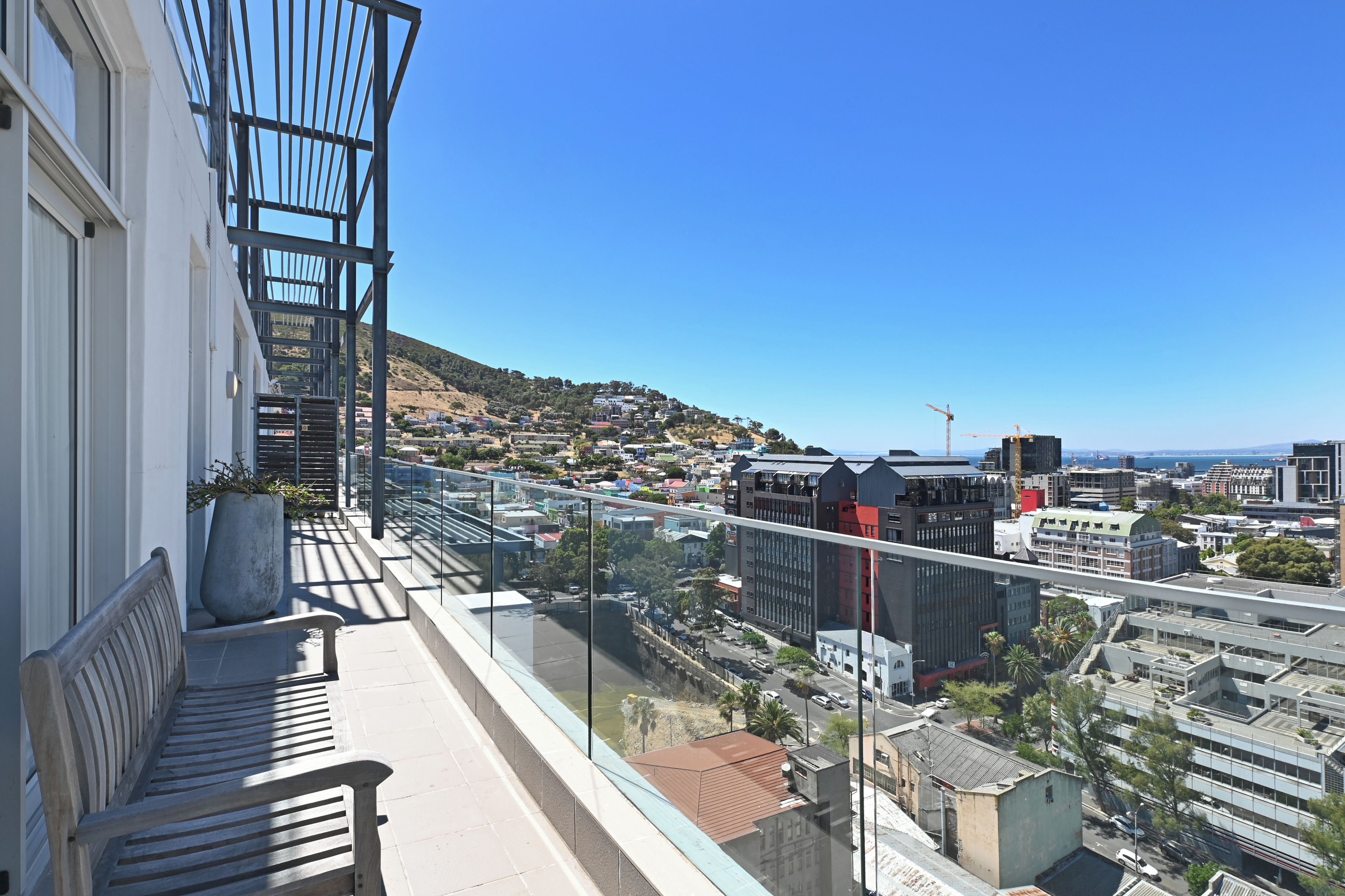 A balcony with a view of a cityscape, including buildings and a distant hill.
