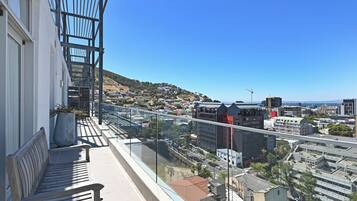 A balcony with a view of a cityscape, including buildings and a distant hill.