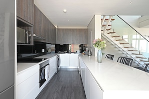 A modern kitchen with a built-in oven, microwave, and stainless steel appliances. - Designer PH with 180° views of City, Mountain & Ocean in Cape Town (Cape Town)