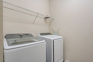 A laundry area with two white front-loading washing machines and a metal drying rack. - 6BR Near Disney Private Pool & Game Room (Kissimmee)
