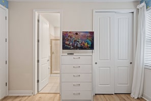 A room with a white door, a white cabinet with drawers, and a flat-screen TV mounted above it. - 6BR Near Disney Private Pool & Game Room (Kissimmee)