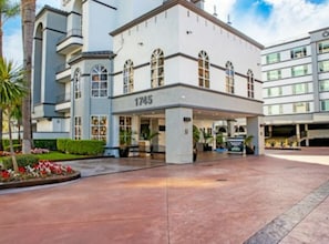 Entrada de hotel con el número '1745' en la fachada, un vestíbulo cubierto y un área ajardinada con flores.