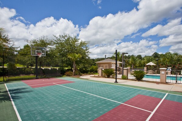 Ein Basketballplatz im Freien mit Pool und einem Gebäude im Hintergrund.
