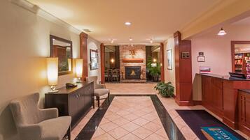 A hotel lobby with a reception desk, seating area, and a fireplace.