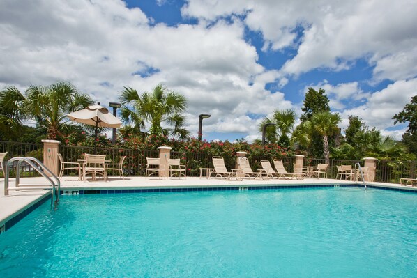 A swimming pool with lounge chairs and umbrellas, surrounded by palm trees and flowers. - Free Breakfast! 1 Bedroom Suite in Tallahassee (Tallahassee)