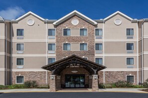 A multi-story hotel with a stone facade, a central entrance with a wooden arch, and multiple windows on each floor. - Free Breakfast! 1 Bedroom Suite in Tallahassee (Tallahassee)