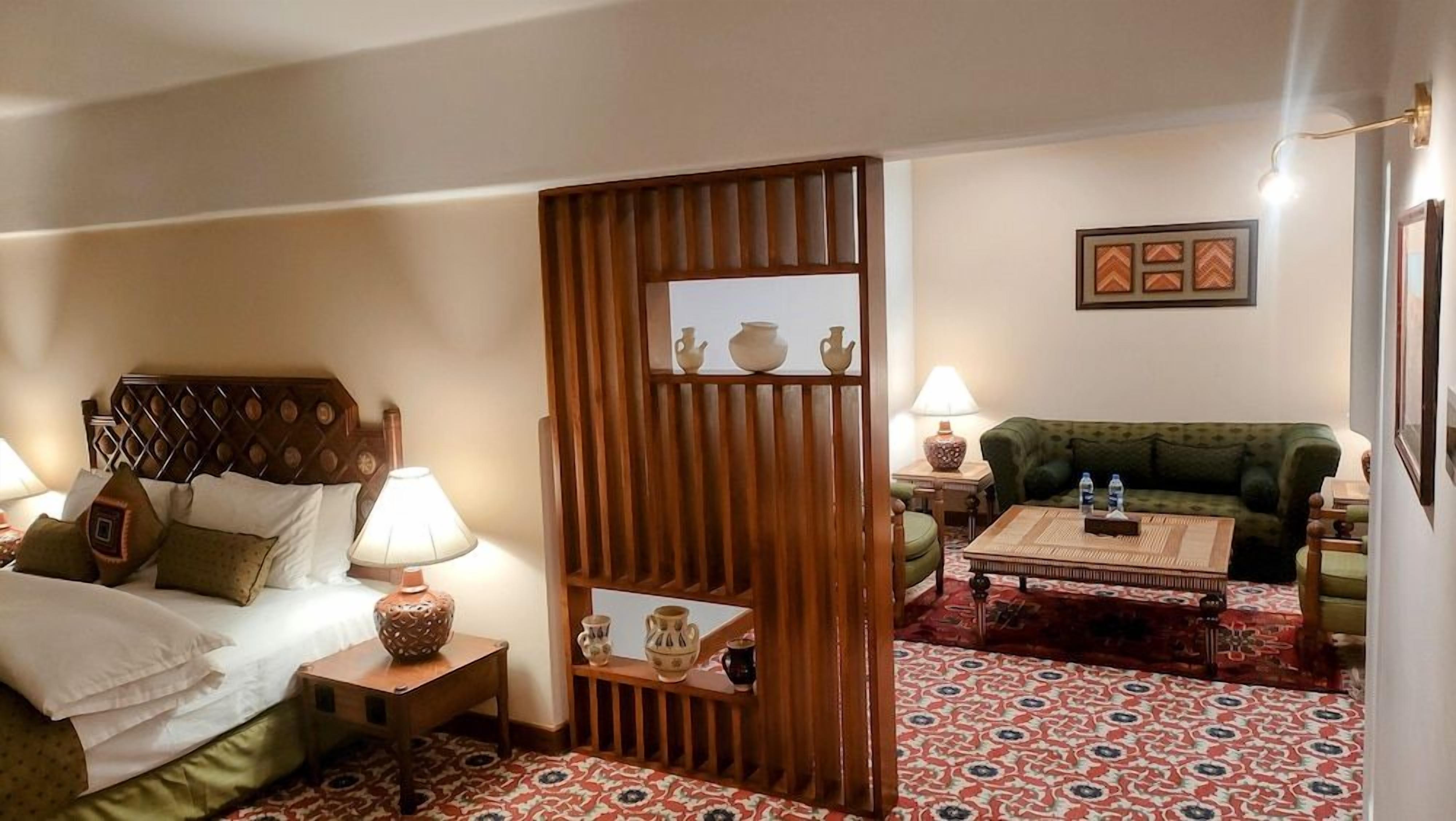 Een hotelkamer met een bed, een bank, een bijzettafeltje en een decoratieve wand.