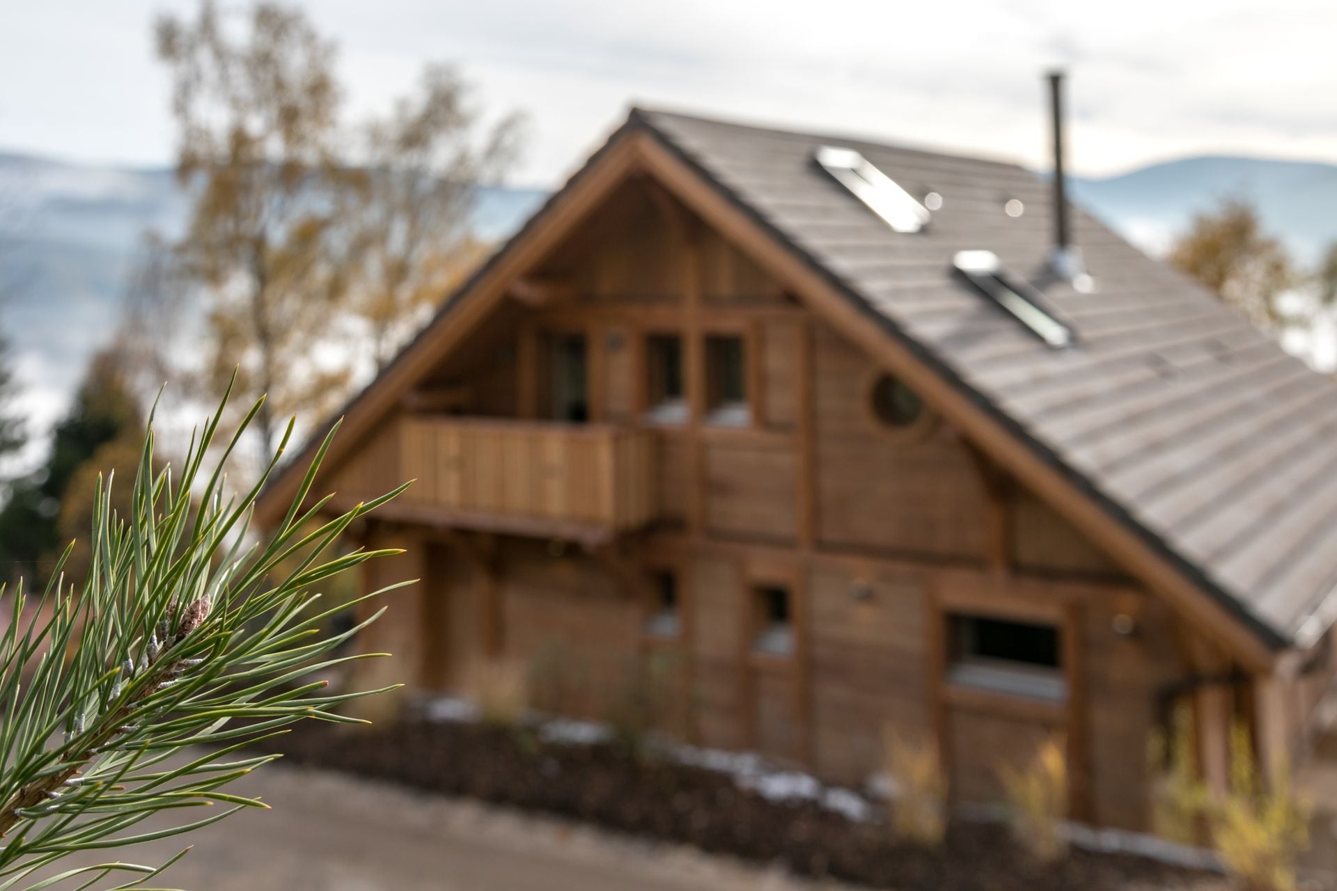 A wooden cabin with a balcony, a chimney, and a view of the mountains.