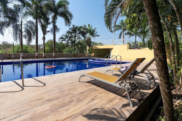 A swimming pool with lounge chairs and palm trees. - Saavaj Resort (Talala)