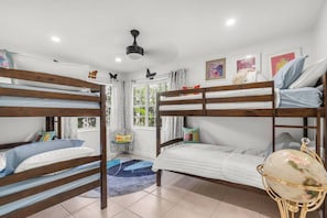 A bunk bed room with a ceiling fan, a small table, and a globe. - Sprawling waterfront estate (Wilton Manors)