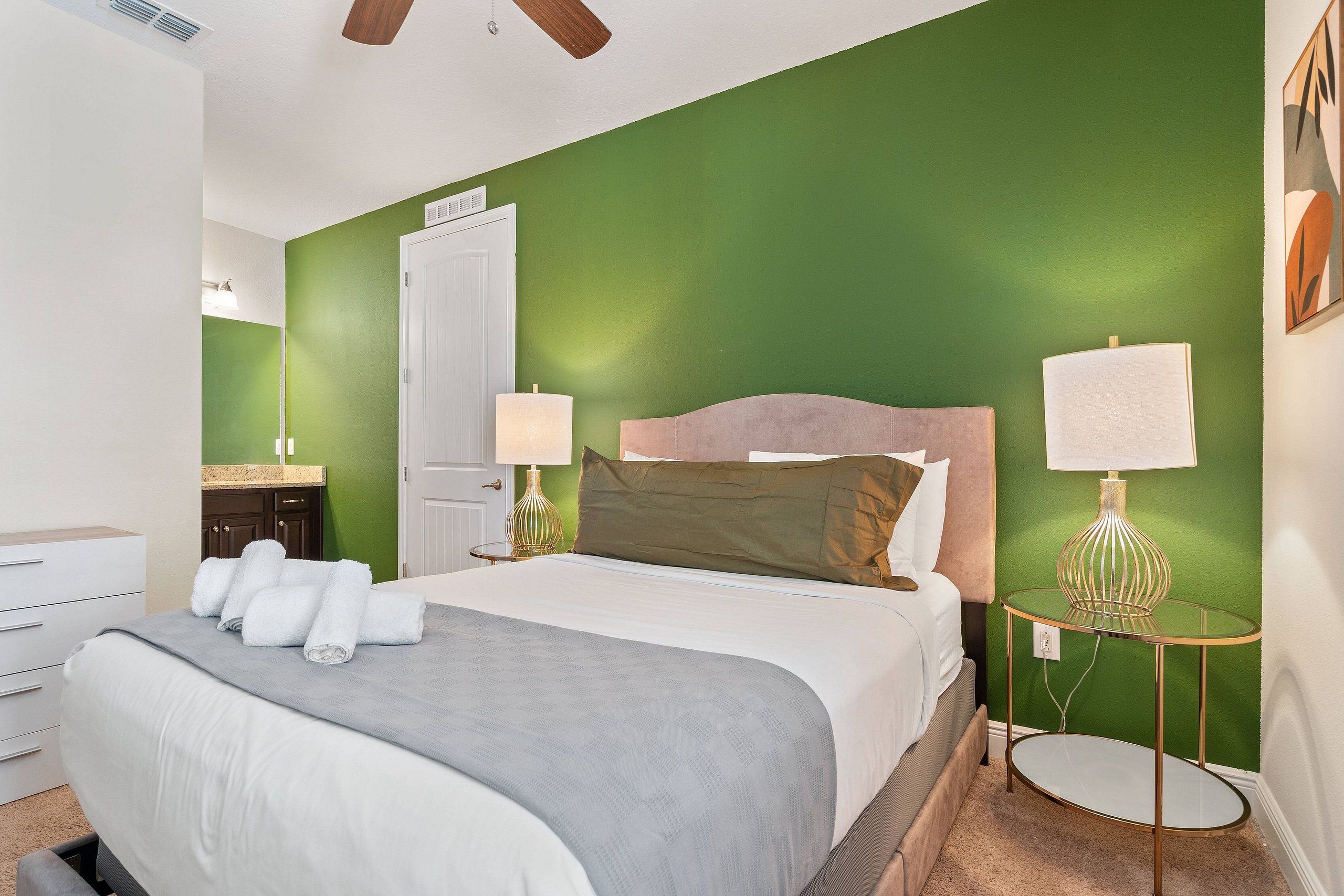 A bedroom with a bed, bedside lamps, a dresser, and a round table.