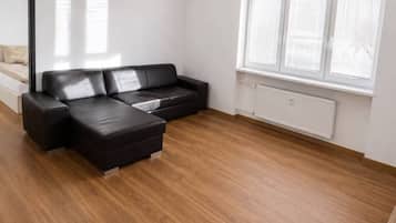 A modern living room with a sectional sofa, a round coffee table, and a large window with blinds.