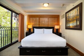 Une chambre d’hôtel avec un grand lit, deux tables de chevet, une fenêtre donnant sur un paysage verdoyant et un tableau au mur.