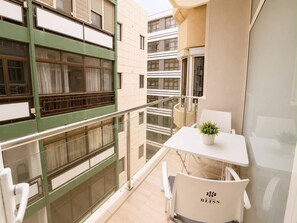 A balcony with a table and chairs, a potted plant, and a view of adjacent buildings. - 402|Apartment with ocean views|Canteras Beach (Las Palmas de Gran Canaria)