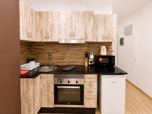 A compact kitchen with wooden cabinets, a stainless steel sink, a black stove, a microwave, and a dishwasher. - 402|Apartment with ocean views|Canteras Beach (Las Palmas de Gran Canaria)