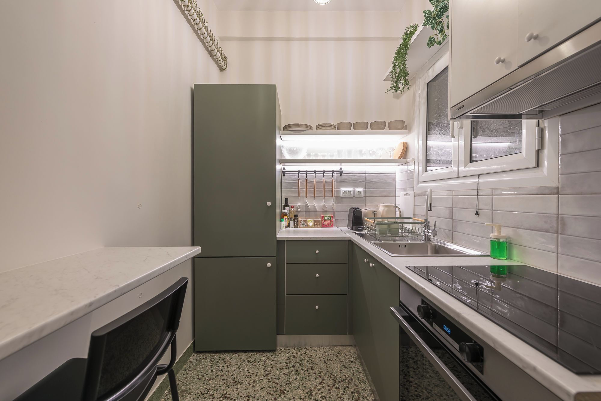 A compact kitchen with a refrigerator, stove, sink, and cabinets.