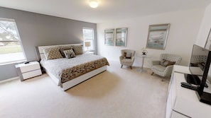 A bedroom with a large bed, two chairs, a small table, and a TV. - 4BR Home in Kissimmee Mickey & Minnie Room (Kissimmee)
