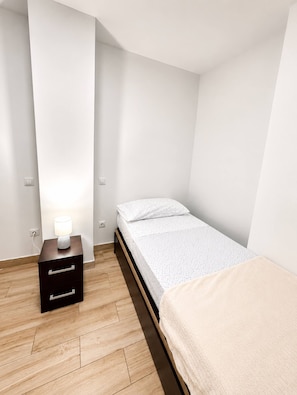A small, modern bedroom with a single bed, a nightstand with a lamp, and a wooden floor. - 403|Apartment with ocean views|Canteras Beach (Las Palmas de Gran Canaria)