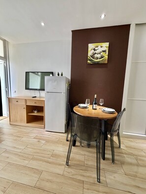 A dining area with a wooden table, clear chairs, a white refrigerator, and a flat-screen TV on the wall. - 403|Apartment with ocean views|Canteras Beach (Las Palmas de Gran Canaria)