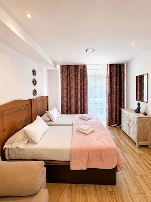 Ein Hotelzimmer mit zwei Betten, einem Holz-Kopfteil, einem kleinen Schrank und einem Fenster mit Vorhängen.