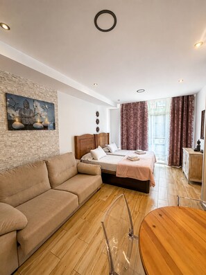 Ein modernes Schlafzimmer mit einem Bett, einer Couch, einem Esstisch und einem an der Wand befestigten Kunstwerk.