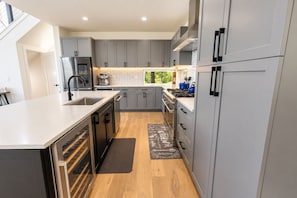 A modern kitchen with grey cabinets, stainless steel appliances, and a wooden floor. - Firefly Overlook | MTN Views + Chef's Kitchen (Young Harris)