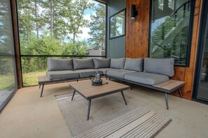 Ein modernes Wohnzimmer mit einem Ecksofa, einem Couchtisch und Blick ins Freie.