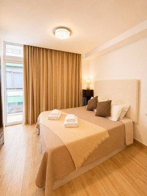A hotel room with a bed, a nightstand, a lamp, and a view of the outdoors through a window. - 502|Apartment with ocean views|Canteras Beach (Las Palmas de Gran Canaria)