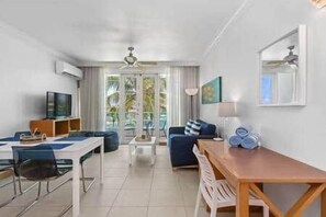 A modern living room with a dining area, a sofa, a TV, and a ceiling fan. - Condado Lagoon-Apt in Condado near to the beach (San Juan)