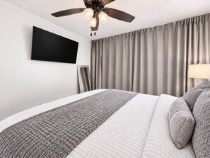 A hotel room with a bed, a ceiling fan, a flat-screen TV, and a window with curtains. - Wake Up to Ocean Views | Dos Marinas (Fajardo)