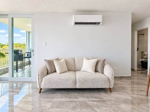Een woonkamer met een bank, een airconditioner en uitzicht op het omliggende landschap.