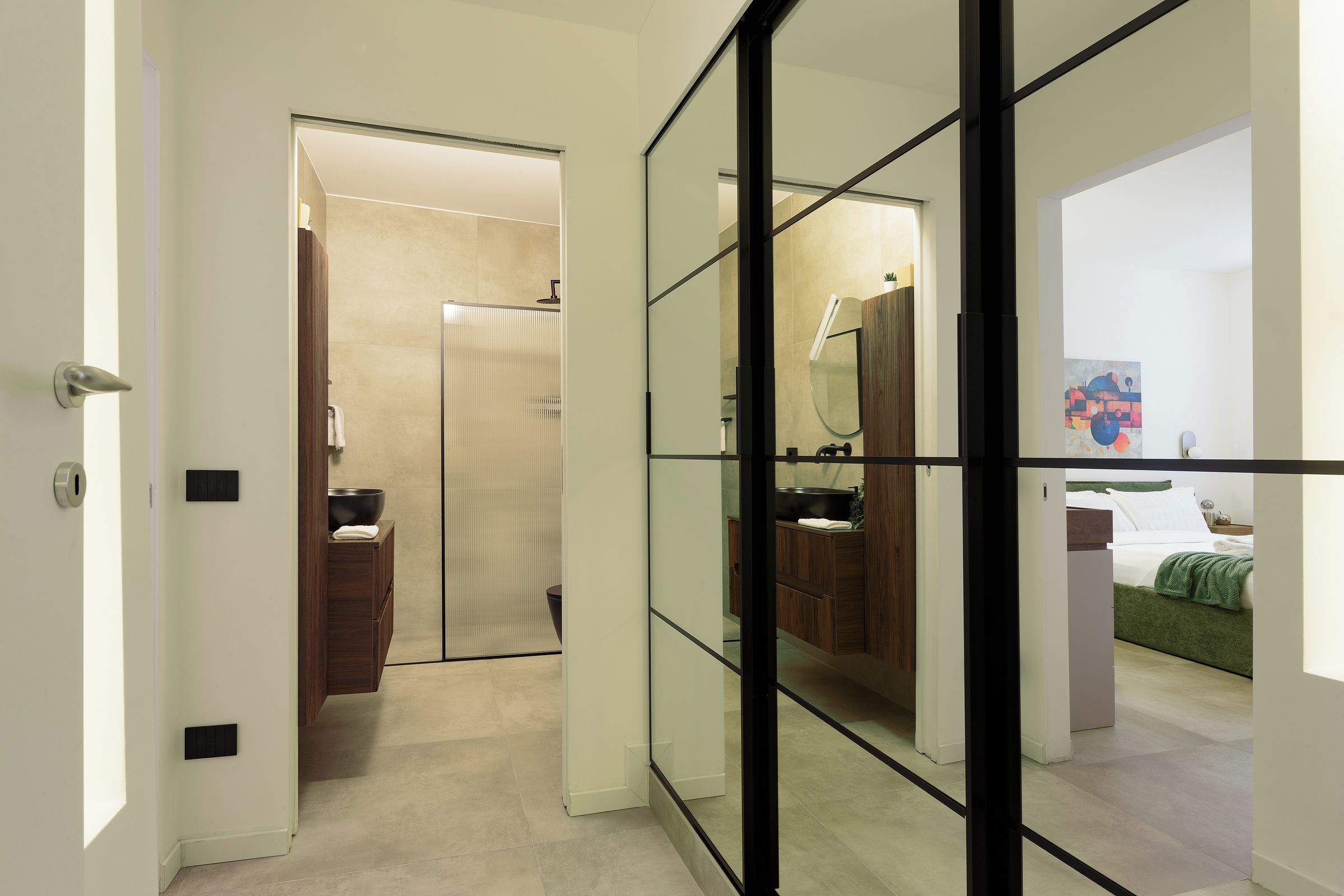 A modern bathroom with a glass partition, a wooden vanity, and a large mirror.