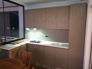 A modern kitchen with a built-in gas stove, a sink, and wooden cabinets. - Sunset Vibes Durrës – Modern Coastal Escape with Breathtaking Views, family frie (Durrës)