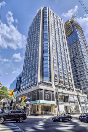 A high-rise building with a prominent 'STK' sign at the ground level, surrounded by urban traffic. - Bright 1-Bedroom | Steps from Shops & Transit (Toronto)
