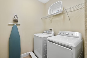 A laundry room with two washing machines, a drying rack, and a hanging iron. - 5BR Near Disney Private Pool, spa & Game Room (Kissimmee)