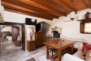 Una sala de estar acogedora con techo de madera, chimenea, televisor y pared de piedra.