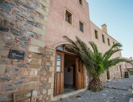 Un edificio de piedra con letrero de cafetería, puertas de madera y una palmera.
