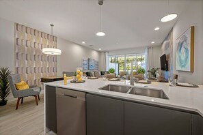 A modern kitchen with a central island, built-in appliances, and a dining area with a view. - 3BR Townhouse Near Disney Pool & Mickey Room (Clermont)