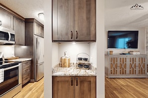 A modern kitchen with wooden cabinets, stainless steel appliances, and a marble countertop. - Renovated 2 Bedroom Sugar Mountain Condo with Fireplace and Easy Access (Sugar Mountain)