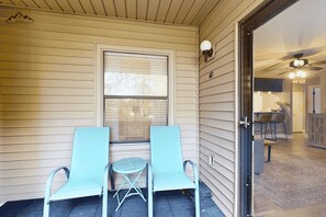 A porch with two chairs and a small table, a window with blinds, and a door leading to an interior space with a ceiling fan. - Renovated 2 Bedroom Sugar Mountain Condo with Fireplace and Easy Access (Sugar Mountain)