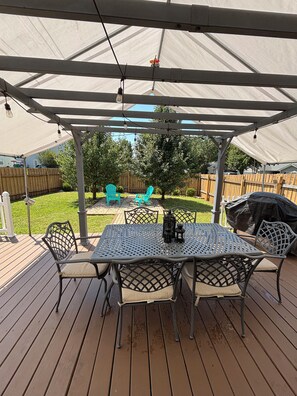 A covered outdoor patio with a table and chairs, a grill, and a wooden deck. - Spacious & Comfortable Home Near Uptown Charlotte (Charlotte)