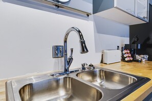 A modern kitchen with a stainless steel sink, a faucet, and a coffee machine. - Historic Brick Loft | Heart of Downtown Knoxville (Knoxville)