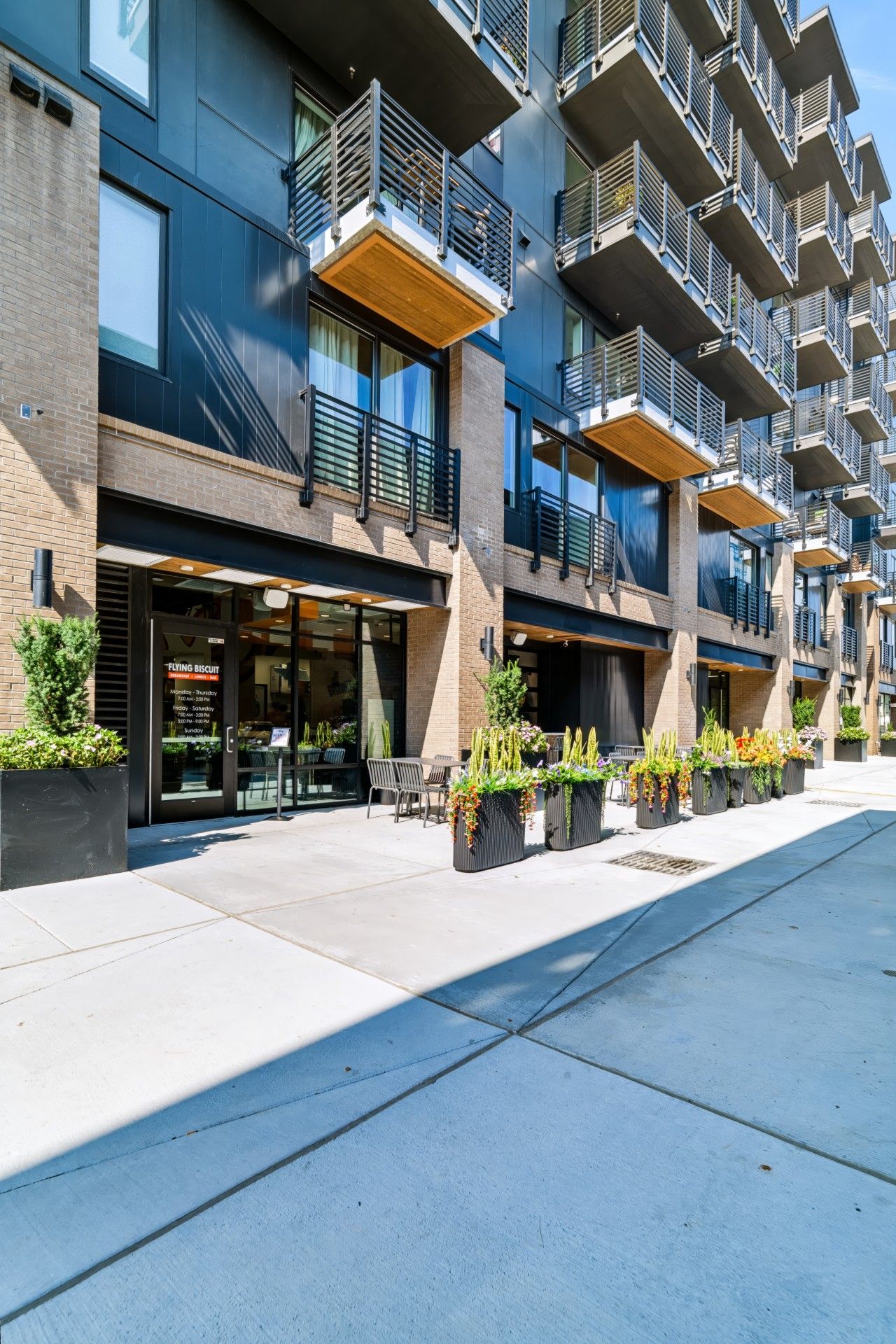 En modern byggnad med flera våningar, utomhusservering och planteringar.