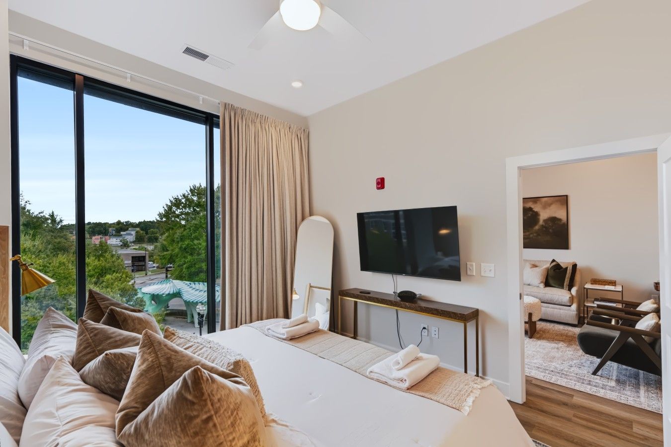 A hotel room with a large bed, a television, and a view of the outdoors.